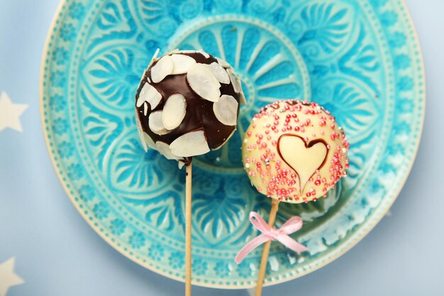 Tasty cake pops on plate, close up