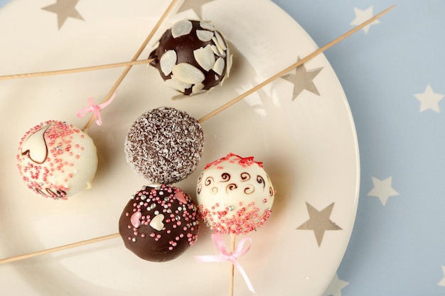 Tasty cake pops on plate, close up