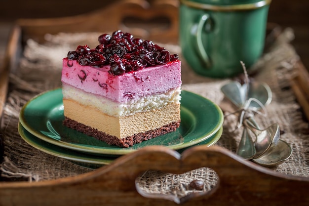 Tasty cake with black currant on rustic wooden tray