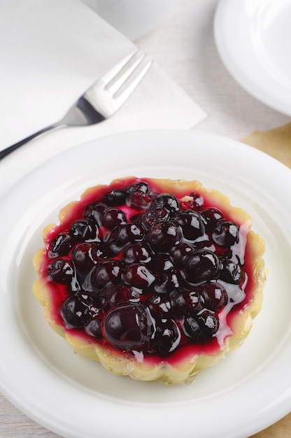 Tasty cake with black currants on white table