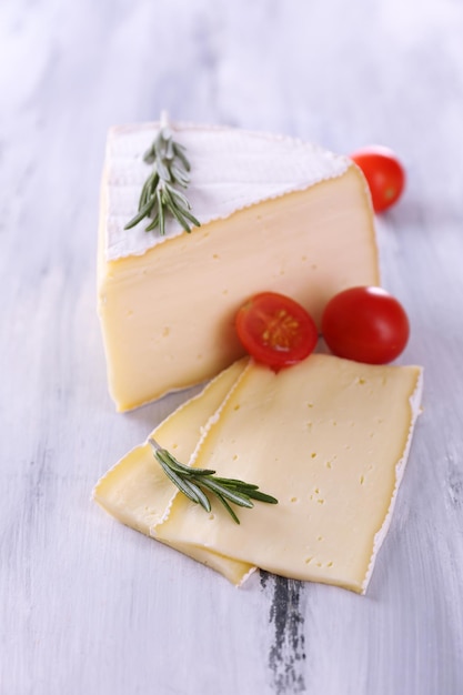 Tasty Camembert cheese with tomato and rosemary on wooden table