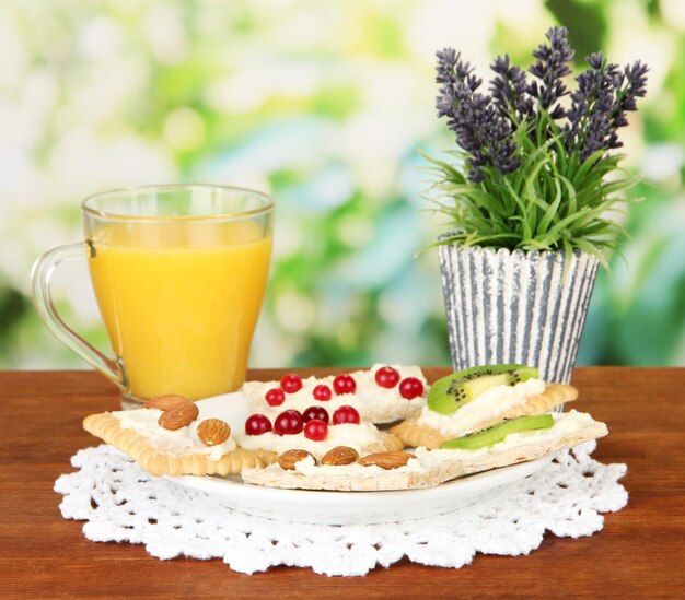 Tasty canapes with cheese kiwi and cranberry almond on color plate on bright background