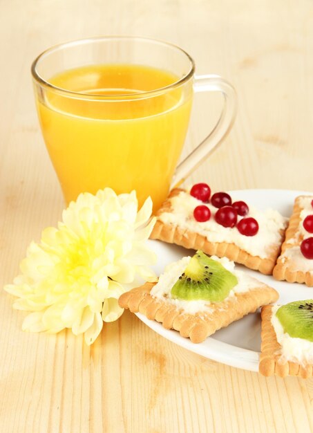 Tasty canapes with cheese and kiwi cranberry on color plate on wooden background