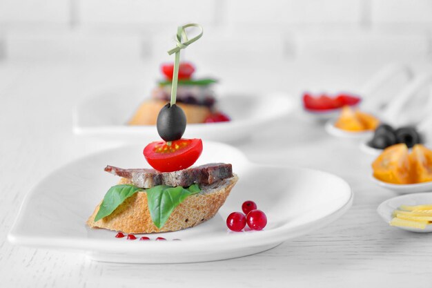 Tasty canapes on wooden table close up