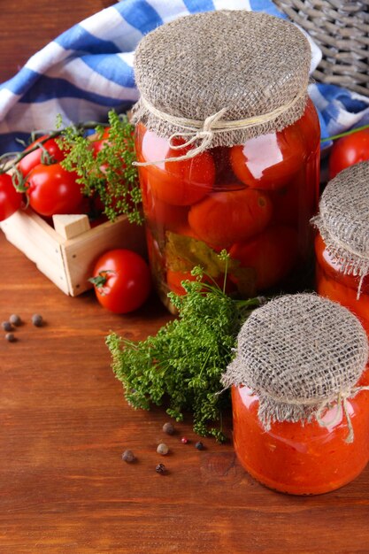 Tasty canned and fresh tomatoes on wooden table