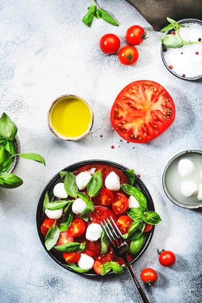 Tasty caprese salad with ripe red tomatoes and mozzarella cheese with fresh green basil leaves Italian food Top view