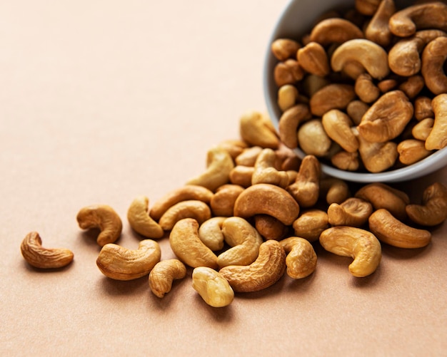 Tasty cashew nuts in bowl on a brown background