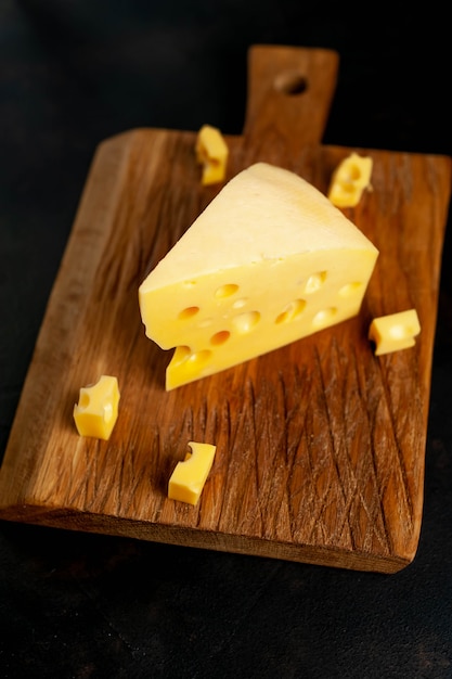 Фото Вкусный сыр на разделочной доске на каменном фоне