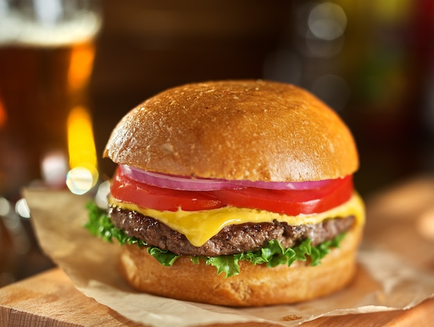 Tasty cheeseburger with beer in background