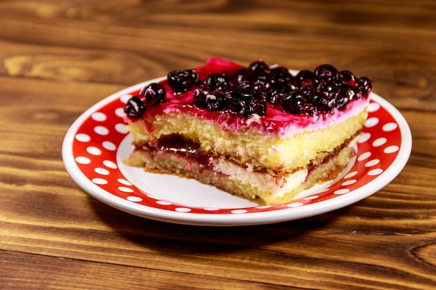 Tasty cheesecake with black currant on wooden table