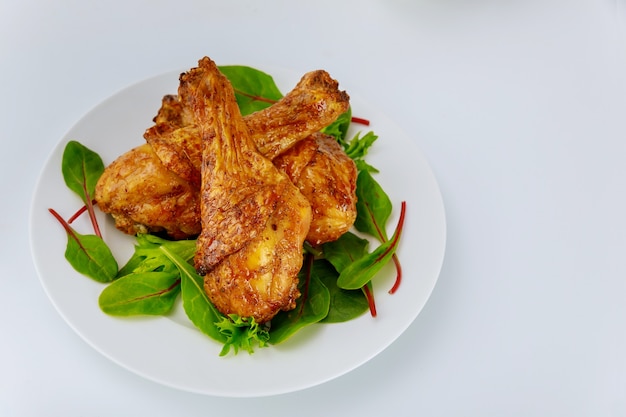 Tasty chicken drumsticks with spinach on white plate.