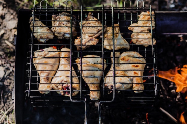 Tasty chicken legs on the grill with fire flames