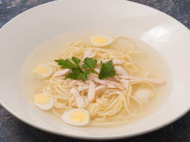 Tasty Chicken soup with homemade noodles on a white plate in a restaurant