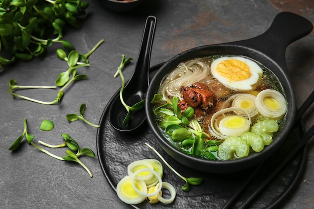 Tasty Chinese soup in bowl on grey table