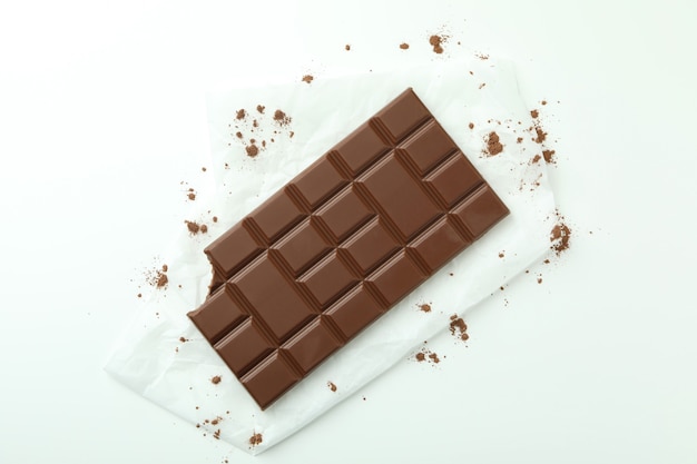 Tasty chocolate bar on paper on white