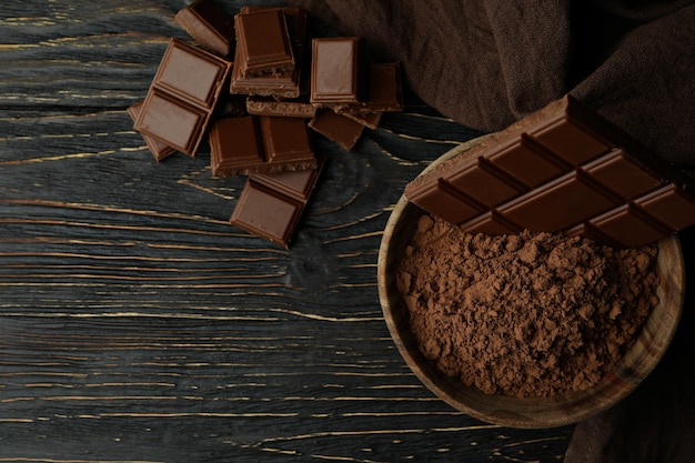 Tasty chocolate bars and powder on wooden table