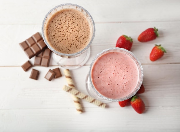 Tasty chocolate and berry cocktail with berries and sweets on light wooden background top view