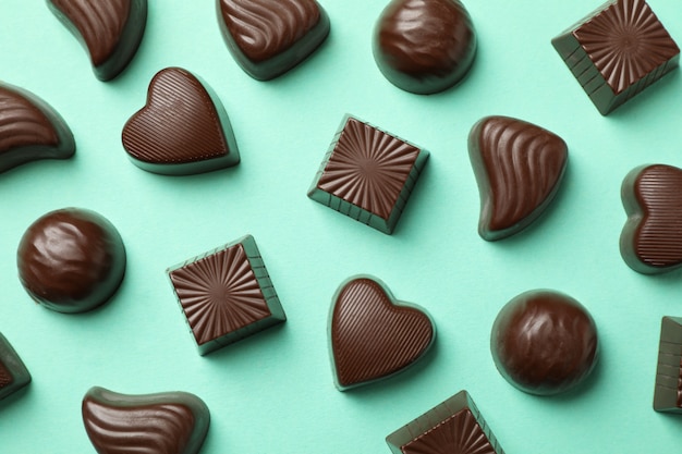 Tasty chocolate candies on mint background, top view