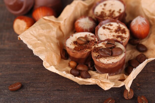 Foto gustose caramelle al cioccolato con chicchi di caffè e noci su fondo di legno