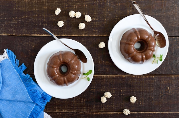 暗い木の表面に白い皿においしいチョコレートプリン。朝食に軽い低カロリーのデザート。平面図、フラットレイアウト。