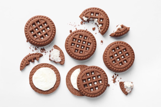 Tasty chocolate sandwich cookies with cream on white background flat lay