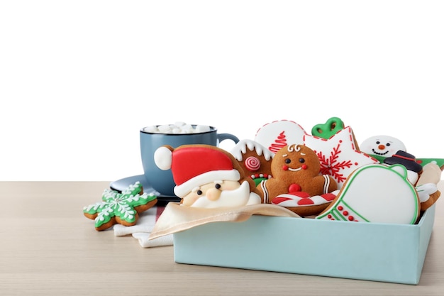 Tasty Christmas cookies and cup of delicious drink on wooden table against white background