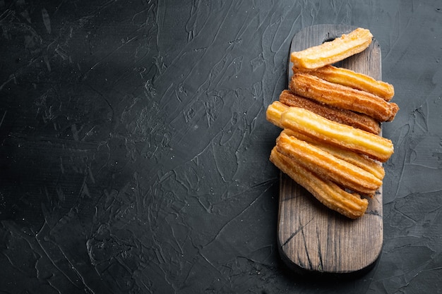 Tasty churros with chocolate caramel sauce set, on black background with space for text, copyspace