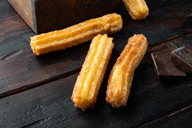 Tasty churros with chocolate caramel sauce set, on old dark wooden table 