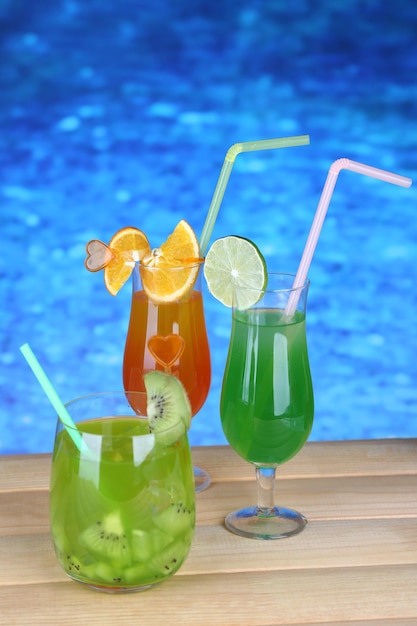 Tasty cocktails on swimming pool background