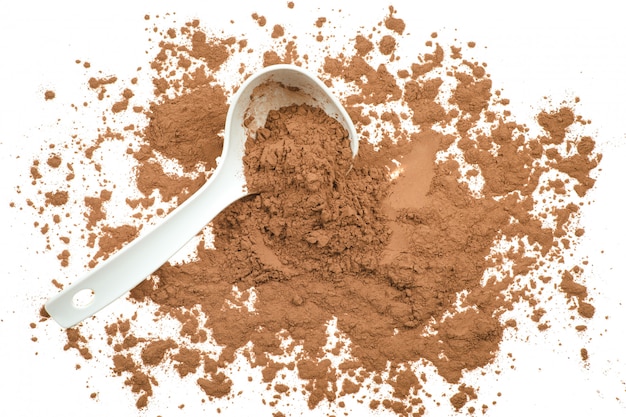 Tasty cocoa powder in spoon isolated on white background