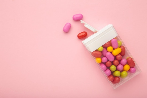 Tasty colored fruit dragee candies with box on pink background