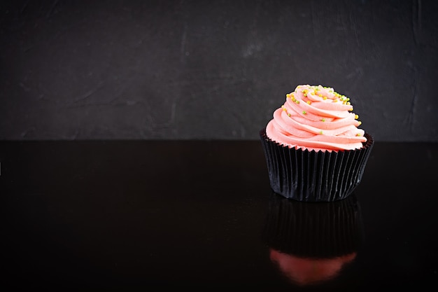 Tasty colorful cupcake isolated on black