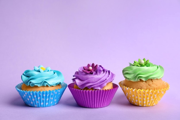 Tasty colorful cupcakes on color background