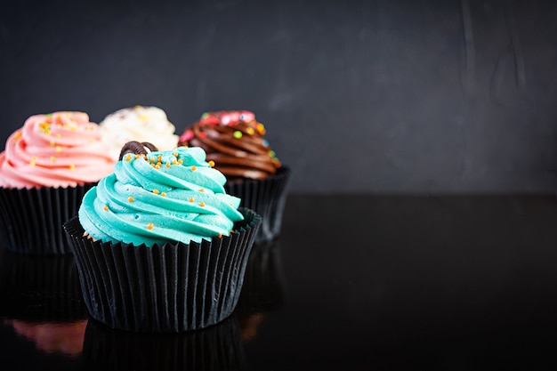 Tasty colorful cupcakes isolated on black