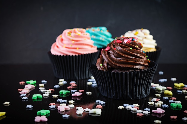 Tasty colorful cupcakes isolated on black