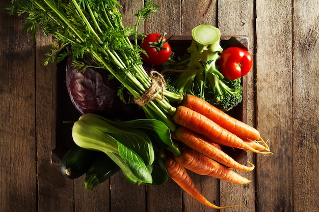 Tasty colorful fresh various seasonal vegetables in wooden box on wooden table. Top View. Cooking Concept. Copy Space.