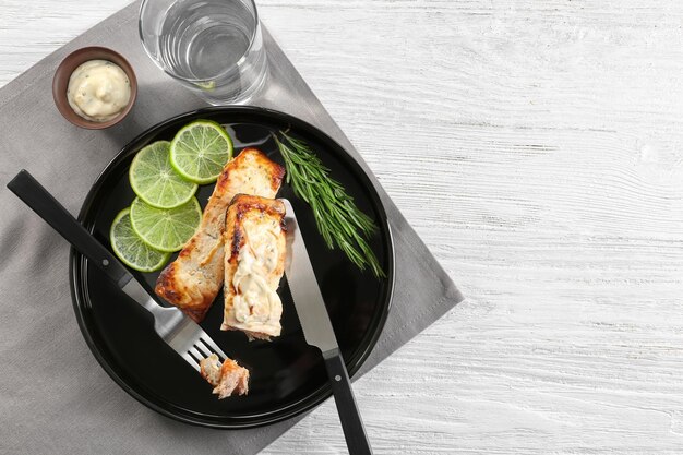 Tasty cooked salmon with slices of lime and rosemary on plate
