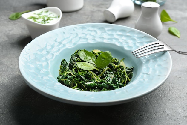 Tasty cooked spinach on grey table Healthy food