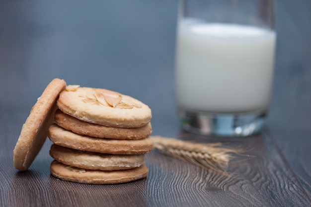 Tasty cookies biscuits with almond and wheat on the plate on  wooden background with glass