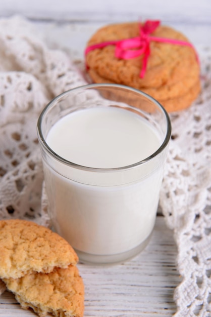 Tasty cookies and glass of milk on color wooden background