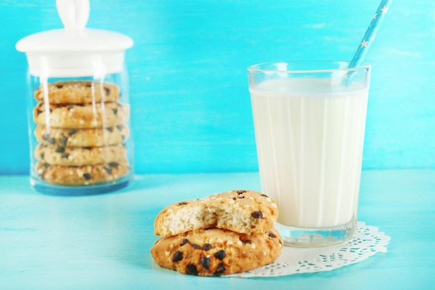 Tasty cookies and glass of milk on color wooden background