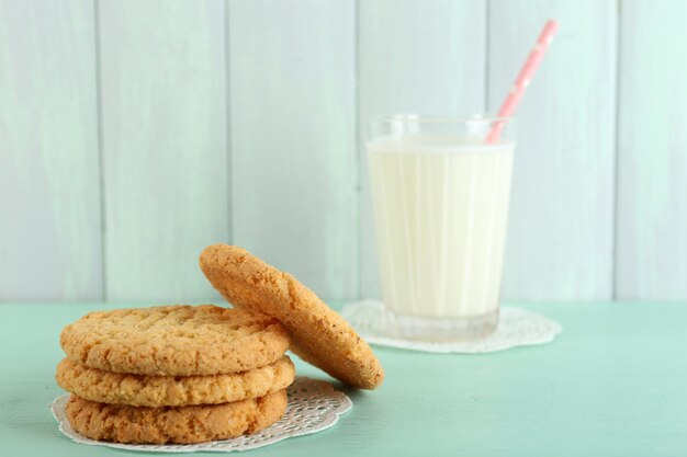 Tasty cookies and glass of milk on color wooden background