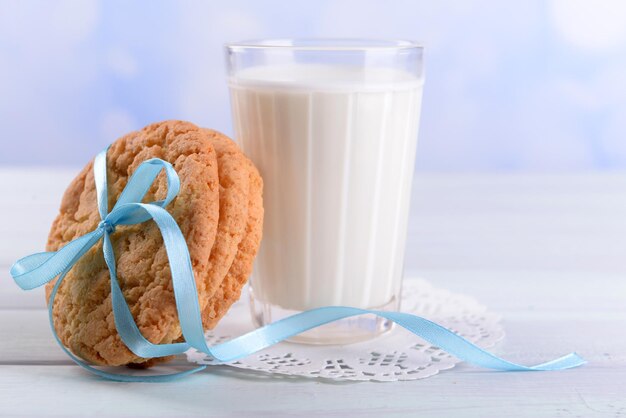 Foto biscotti gustosi e bicchiere di latte sul tavolo in legno colorato su sfondo luminoso