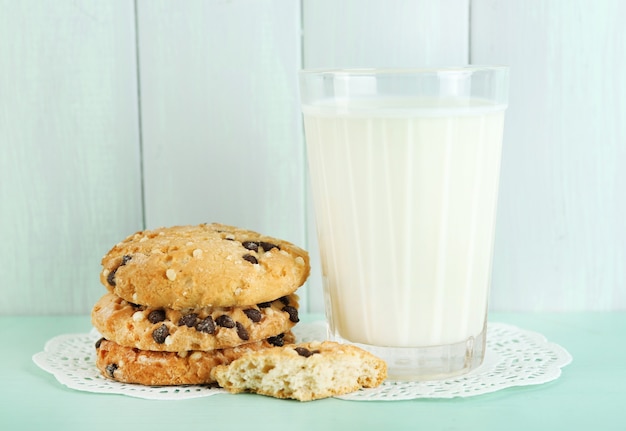 Tasty cookies and glass of milk on color wooden