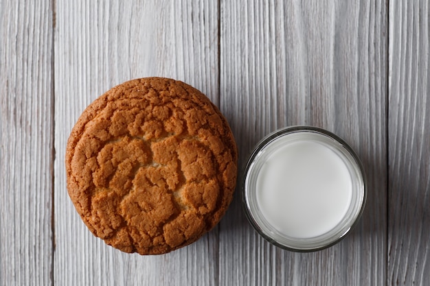 Gustosi biscotti e un bicchiere di latte in un vetro trasparente su uno sfondo bianco rustico copia spazio piatto laici