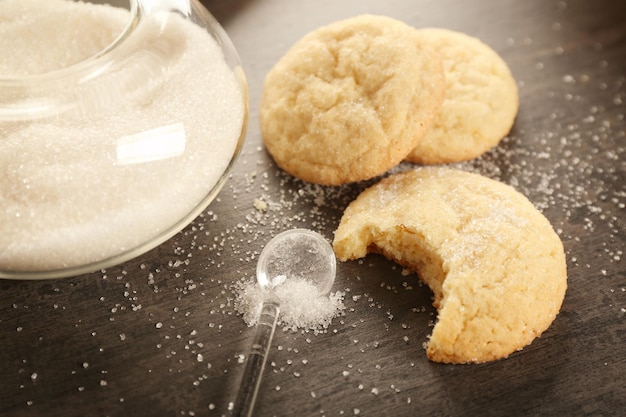 Tasty cookies with spoon and sugar on table