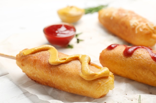 Tasty corn dogs with sauces on table closeup