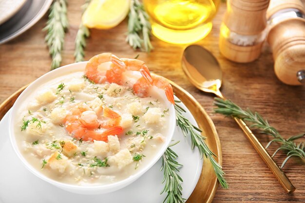 Tasty cream soup with fresh shrimps and croutons in bowl on table