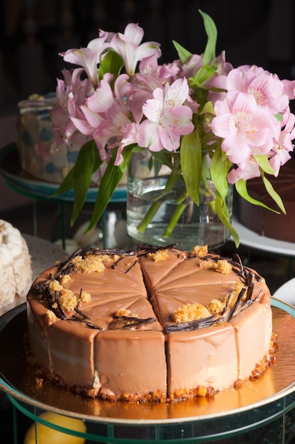 Tasty creamy sponge cake with caramel glaze and pink flowers