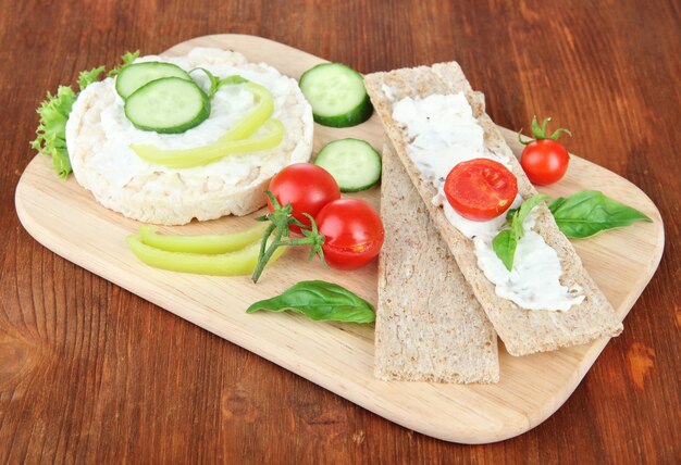 Tasty crispbreads with vegetables on wooden